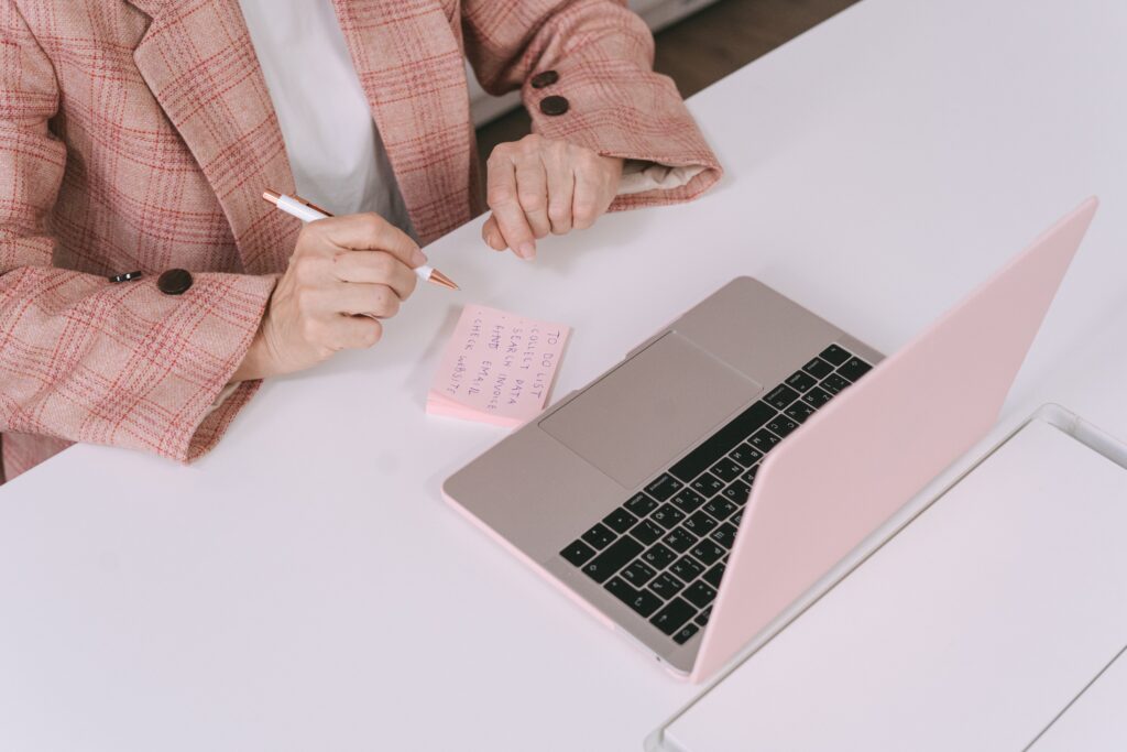 girl researching on laptop with pen and paper